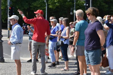 Berlin Almanya 06.17.2025, kırmızı gömlekli bir erkek rehber Berlin, Almanya 'da bir şehir turu sırasında bir grup turistle konuşuyor..