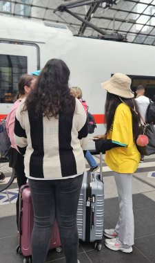 Berlin Almanya 07.15.2025, Berlin tren istasyonunda arkadaşlarıyla şapkalı esmer kadın.