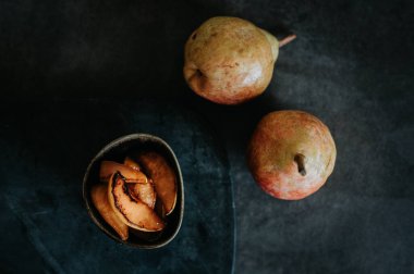 Fırında armut ve arka planda bahçeden iki taze armut.
