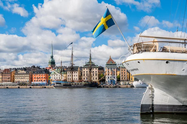 Old ship with a flag of Sweden in foreground, with another big sailing ship anchored in Stockholm