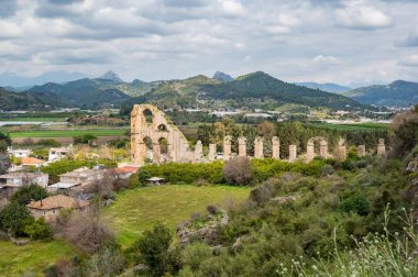Antalya yakınlarındaki Aspendos kompleksinde arka planda dağlarla birlikte eski Roma su kanalı, Türkiye