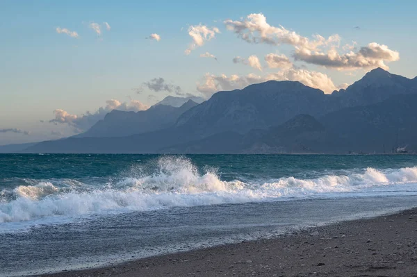 Waves on Konyaalti beach in Antalya with mountains covered in sn
