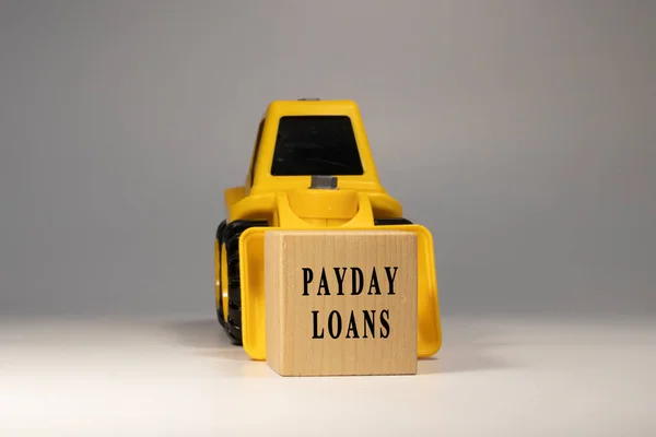 Payday loans text. It is written on a wooden surface. The background is white