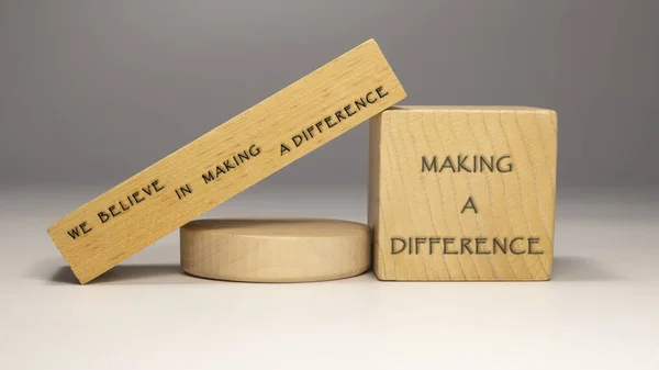 The sentence We believe in making a difference was written. Wooden concept studio shoot.