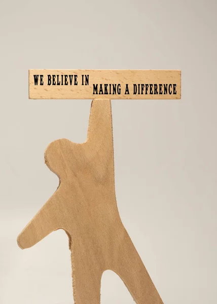 The sentence We believe in making a difference was written. Wooden concept studio shoot.