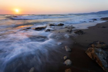 Gün batımında uzun pozlama tekniğiyle çekilmiş bir deniz manzarası..
