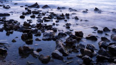 Gün batımı ve deniz taşları. Fotoğraf, uzun pozlama tekniğiyle çekildi..