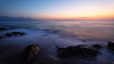 Gün batımında uzun pozlama tekniğiyle çekilmiş bir deniz manzarası..