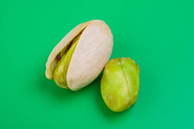 pistacho abierto con otro fruto al lado sobre fondo verde