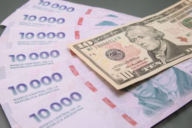 Birkaç bin Arjantin pesosu yığını ve karanlık arka planda 100 dolar. Peso ve dolar arasındaki ilişki, Kavram Dolar Blue