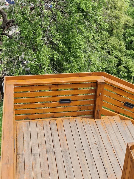 Açık kahverengi ahşap teras ve ağaçlar..