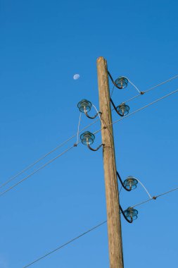 Ahşap bir elektrik direği, mavi bir arka planda, arka planda ay var..