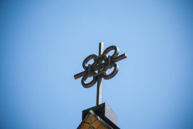 Binanın tepesinde eşsiz bir metal haç. Merkezinde açık bir gökyüzüne karşı birbirine bağlı dört daire var..