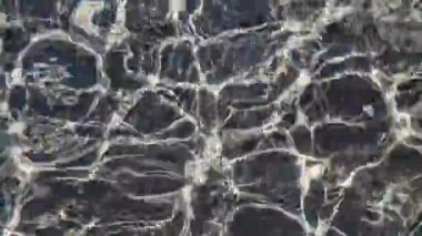 Güneş ışığının karanlık dalgalanan su yüzeyindeki yansımalarının soyut dokusu. Parıldayan çizgiler ve dalgalar doğal bir sıvı deseni oluşturur. Hareketi, berraklığı ve dingin su güzelliğini yakalar.