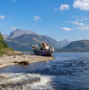 Corpach, Fort William, Highlands, İskoçya 'daki eski balıkçı teknesi İngiltere' nin en yüksek dağı Ben Nevis 'i gösteriyor.