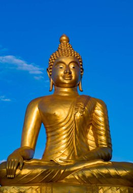 Oturan bir Buda 'nın altın heykeli, parlak mavi gökyüzüne karşı huzur içinde gülümsüyor..