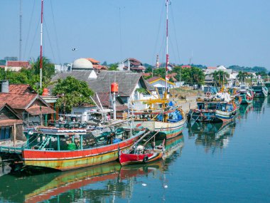 Jepara, Endonezya - 5 Temmuz 2015: Evlerle çevrili, nehir kıyısında renkli tekneleri olan geleneksel bir balıkçı köyü.