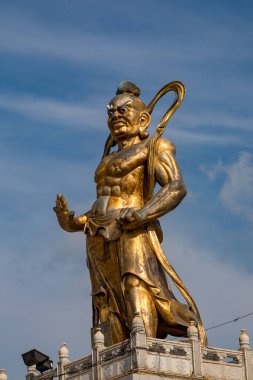 Bulutlu mavi gökyüzüne karşı efsanevi bir koruyucu olan ayakta duran Yaksha 'nın altın heykeli. Heykel, Tayland tapınağı sanatının ve kültürünün güçlü bir gösterisidir. Malezya, Penang