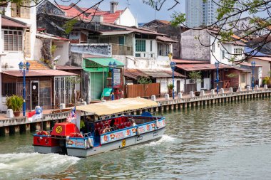 Melaka nehri boyunca renkli binalarla tekne gezintisi.
