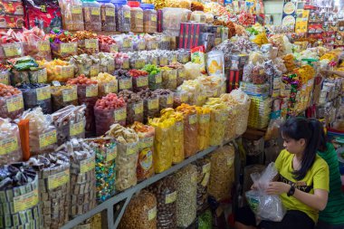 Pazarda çeşitli renkte kurutulmuş ürünler paketleyen kadın.