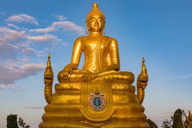 Oturan bir Buda 'nın altın heykeli, parlak mavi gökyüzüne karşı huzur içinde gülümsüyor..