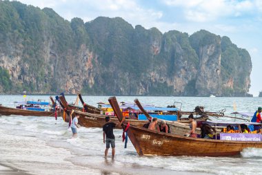 Tayland. Okyanusta ahşap uzun kuyruklu tekneler ve arka planda kayalık kayalıklar. 