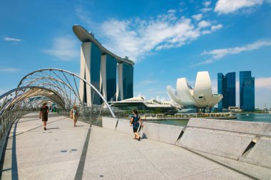 Arka planda Marina Bay Sands oteli ile Helix Köprüsü 'nde yürüyen turistler ve yerliler. Singapur