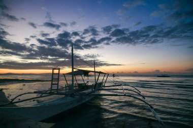 Bohol, Filipinler - 21 Nisan 2018: Filipinler 'in Panglao Adası' ndaki Alona Sahili 'nde demirli geleneksel iskele teknesinde gün batımı manzarası.