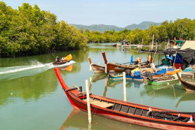 Jet ski, tropikal bir nehirde mangrov ormanları olan geleneksel demirli tekneleri geçiyor. Tayland, Phuket