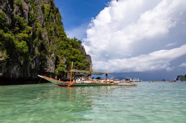 Yüksek Kireçtaşı Kayalıkları ve Geleneksel Filipin Kayığı, Palawan, Filipinleri olan Tropikal Göl