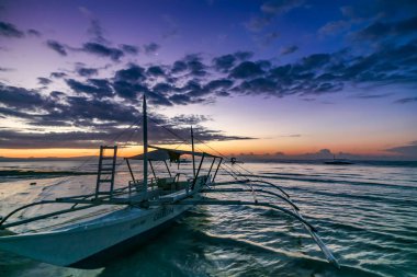 Bohol, Filipinler - 21 Nisan 2018: Filipinler 'in Panglao Adası' ndaki Alona Sahili 'nde demirli geleneksel iskele teknesinde gün batımı manzarası.