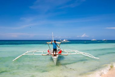 Bohol, Filipinler - 21 Nisan 2018: Filipinler, Panglao Adası 'ndaki Alona Sahili' nde geleneksel bir teknede duran adam. 