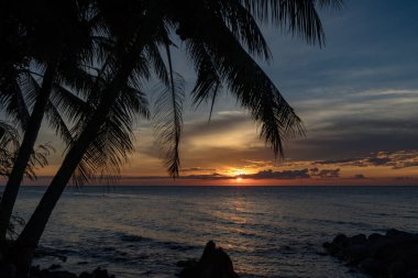 Parlayan ufuk ve sakin dalgalarla huzurlu bir sahil akşamı kıyıda, Camiguin, Filipinler