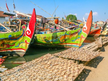Jepara, Endonezya - 5 Mayıs 2018: Dar bir nehir boyunca dizilmiş renkli tekneleri olan geleneksel bir balıkçı köyü, evlerle çevrili..