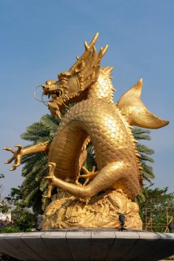 Phuket 'teki altın ejderha heykeli palmiye ağaçlarıyla çevrili.