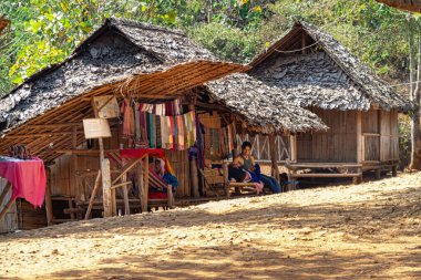 İnsanlar geleneksel ahşap kulübelerin, Tayland Tepesi kabilelerinin dışında dinleniyorlar.