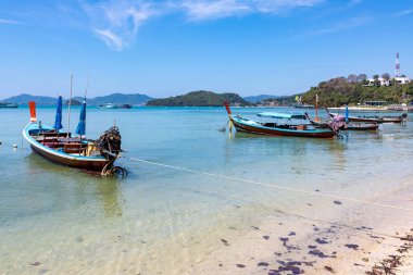 Geleneksel tekneler mavi gökyüzünün altında Phuket sahiline demirlediler.
