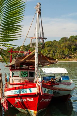 Berrak gökyüzünün altında tropik kıyı şeridine yanaşan renkli ahşap botlar, Koh Chang, Tayland