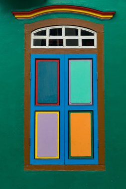 Yeşil duvara karşı geometrik paneller içeren renkli pencere çerçevesi, Küçük Hindistan, Singapur