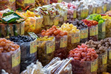 Kalabalık pazarda renkli kurutulmuş meyveler sergileniyor
