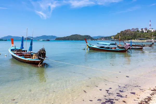 Geleneksel tekneler mavi gökyüzünün altında Phuket sahiline demirlediler.
