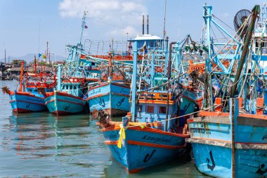 Geleneksel mavi ahşap balıkçı tekneleri, güneşli bir limana demirlemişti.