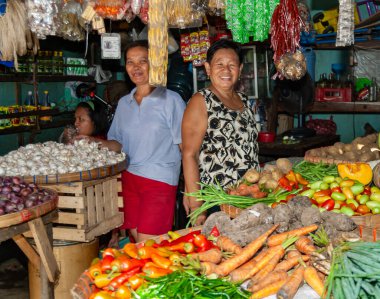 Filipinler 'deki Yerel Asya Pazarı' nda Taze Ürün Tezgahının Arkasında İki Gülümseyen Kadın Satıcı