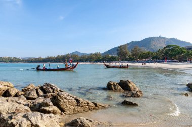 Kayaları, berrak suları ve körfezde geleneksel uzun kuyruklu tekneleri olan tropik plajlar.