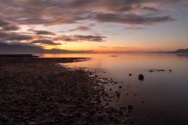 Sakin su rengarenk günbatımını yansıtıyor bulutlu gökyüzü, Filipinler Güney Leyte