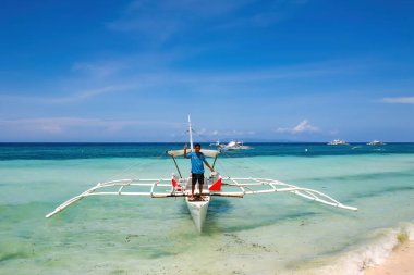 Bohol, Filipinler - 21 Nisan 2018: Filipinler, Panglao Adası 'ndaki Alona Sahili' nde geleneksel bir teknede duran adam. 