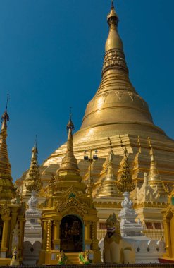 Açık mavi gökyüzünün altında detaylı oymalarla süslenmiş göz kamaştırıcı altın ve beyaz bir koleksiyon. Myanmar.