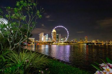 Geceleri dönme dolabı olan Singapur silueti