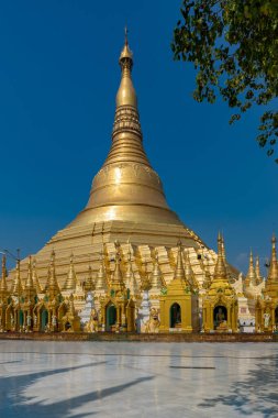 Açık mavi gökyüzünün altında detaylı oymalarla süslenmiş göz kamaştırıcı altın ve beyaz bir koleksiyon. Myanmar.