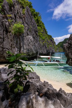 Yüksek Kireçtaşı Kayalıkları ve Geleneksel Filipin Kayığı, Palawan, Filipinleri olan Tropikal Göl